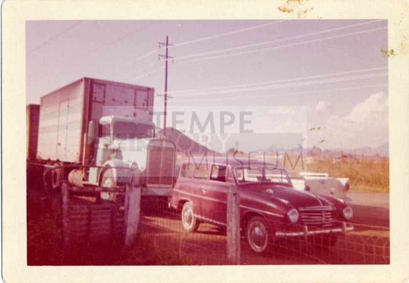 Picture of a late 50s Station Wagon in front of a comercial truck