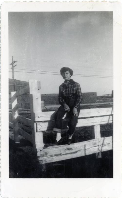 Genevieve Puerta sitting on wooden fence