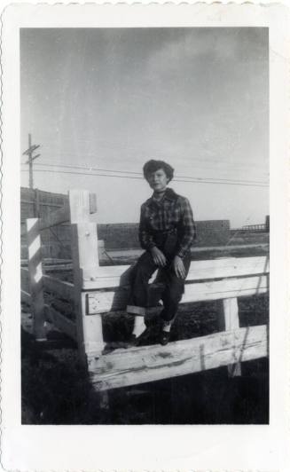 Genevieve Puerta sitting on wooden fence