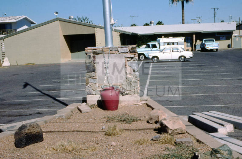 Unknown Brown Building with Parking Lot, Flag Pole and a Red Vase In-Front