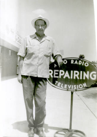 William Hertenstein by his Radio Shop sign