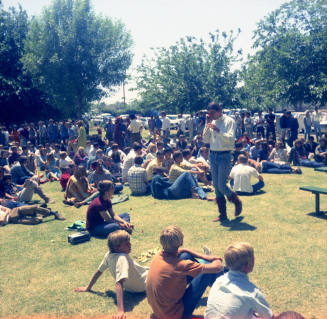 Love-in at Tempe Beach Park--people sitting on grass, 1 man standing/walking