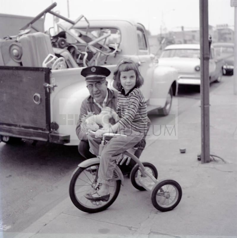 Street Scene with Young Girl on a Tricycle and Uniformed Man on Mill Avenue