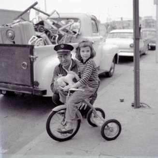 Street Scene with Young Girl on a Tricycle and Uniformed Man on Mill Avenue