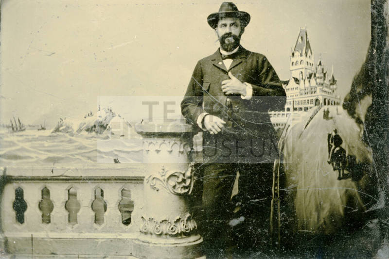 Tintype of Dr. Fenn J Hart in a suit and Stetson hat posing in front of a faux winter landscape