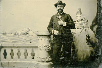 Tintype of Dr. Fenn J Hart in a suit and Stetson hat posing in front of a faux winter landscape