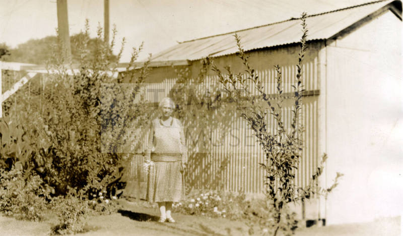 Rosa Brown Hart, wife of Dr. Fenn J Hart, standing in front of a shed outside their home in Phoenix