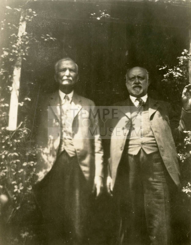 Thomas Knight and Dr. Fenn J Hart standing under a floral entrance way at Mr. Knight's home in San Francisco