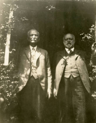 Thomas Knight and Dr. Fenn J Hart standing under a floral entrance way at Mr. Knight's home in San Francisco