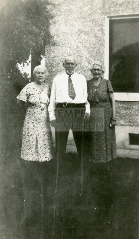 Group photo of Dr. Fenn J Hart standing outside a house with his wife Rosa Brown Hart, and an unkown elderly female