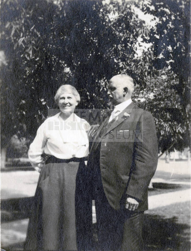 Snapshot of Dr. Fenn J Hart standing under a tree beside his smiling wife Mrs. Rosa Brown Hart