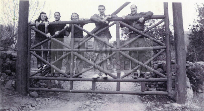 Group photo of Mildred Hart Wilson, daughter of Tempe's first mayor Dr. Fenn J Hart, and her family posing outside together on top of a large wooden gate