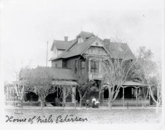 Three adults pictured in front of a house