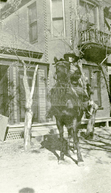 Woman riding horse in front of Petersen house