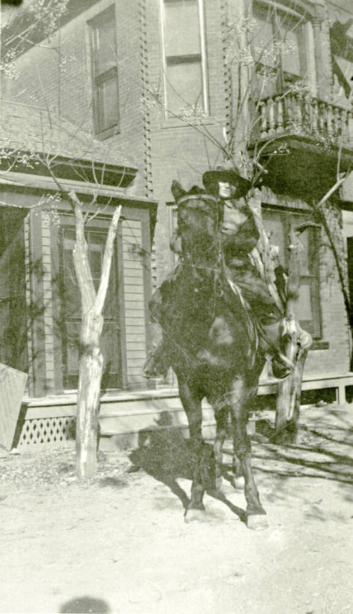 Woman riding horse in front of Petersen house