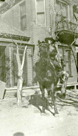 Woman riding horse in front of Petersen house