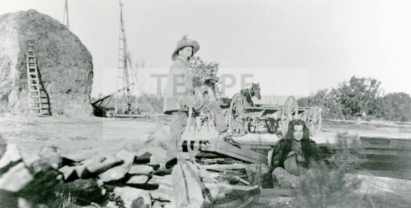 A man and woman standing and sitting on Petersen property.