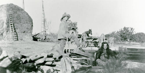 A man and woman standing and sitting on Petersen property.