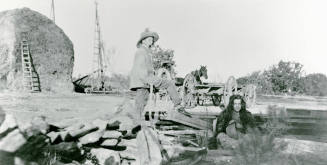 A man and woman standing and sitting on Petersen property.