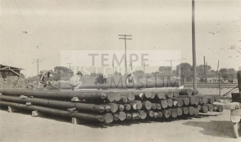Photo- Men stacking power line poles