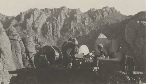 Workers stringing wire from truck in mountains
