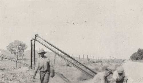Photo-View of bent power line poles with a repair crew working on them