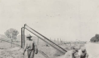 Photo-View of bent power line poles with a repair crew working on them