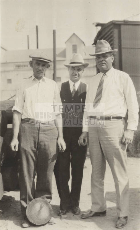 Photo- View of three unidentified men posed in front of a building