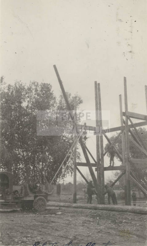 Photo- View of crane hoisting wooden poles at a pole treating plant