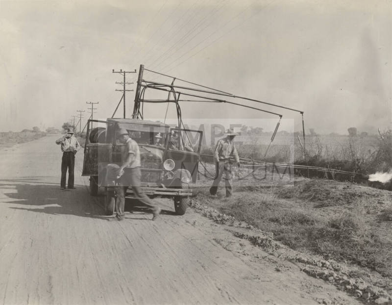 Photo-View of three man crew with truck burning weeds along side of road