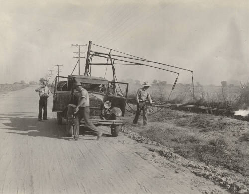 Photo-View of three man crew with truck burning weeds along side of road