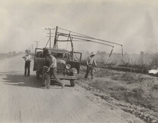 Photo-View of three man crew with truck burning weeds along side of road
