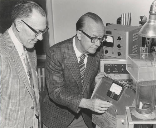 Dr. John Decker demonstrates his photosynthesis measuring device to Dr. Ira Judd
