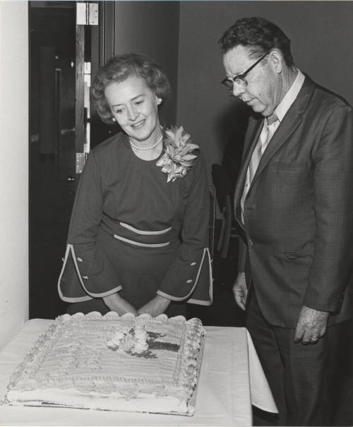 V.P. Gilbert Cady stands in front of cake for Mrs. Keith Rhodes, retired