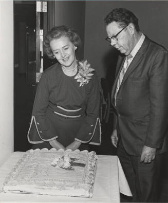 V.P. Gilbert Cady stands in front of cake for Mrs. Keith Rhodes, retired